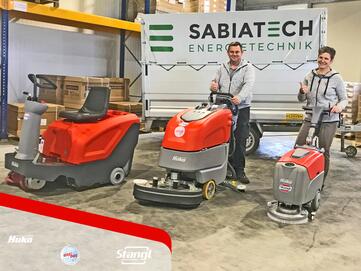 Mitarbeiter bei der Übergabe von Bodenreinigungsmaschinen und einer Kehrmaschine von Stangl
