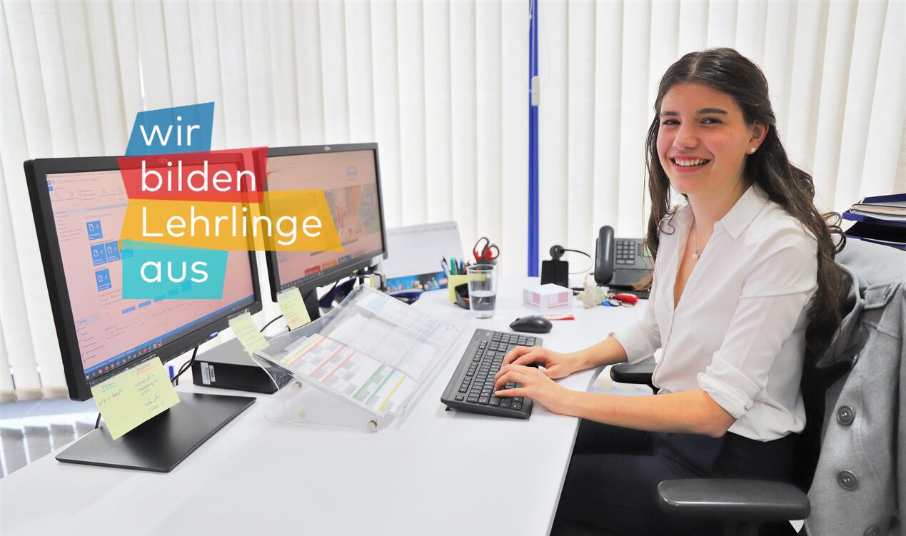 Stangl Lehrling Bürokauffrau Selina Hattinger am Schreibtisch bei der Arbeit mit Logo wir bilden Lehrlinge aus