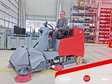 Mitarbeiter bei der Übergabe einer Aufsitz-Scheuersaugmaschinen von Stangl mit einer Kehreinheit