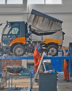 Ein Mitarbeiter des Kundendienst Werkstatt repariert eine Kommunalmaschine